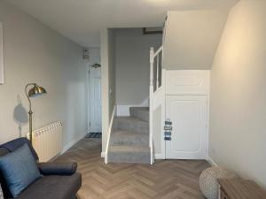 a living room with a staircase and a couch at 1 Bed House On The Beach in St Peter