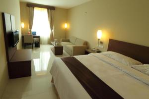 a hotel room with a bed and a living room at Triniti Hotel Jakarta in Jakarta