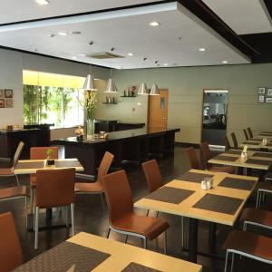 a restaurant with tables and chairs and a piano at Triniti Hotel Jakarta in Jakarta