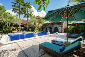 a pool with a chair and an umbrella next to it at Svarga Bebek Villas in Ubud