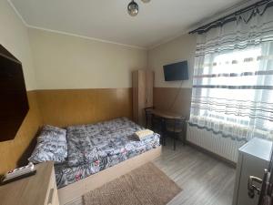 a bedroom with a bed and a table and a window at Бордуляка 11 in Ternopil