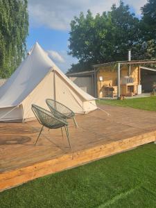 a tent and a chair on a wooden deck at Glamping met paarden in Nieuwerkerken
