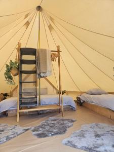 a tent with a ladder and rugs in a room at Glamping met paarden in Nieuwerkerken