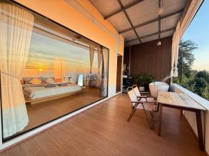 a bedroom with a bed and a large window at ไร่ชาอาโซ -ที่พักดอยช้าง in Ban Huai Khai