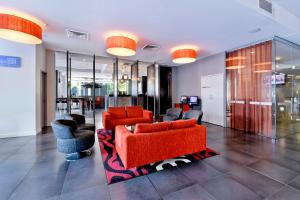 a living room with orange furniture and chairs at Mantra Pandanas in Darwin