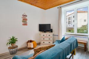 a living room with a blue couch and a tv at Gouveia Cottage in Seixal