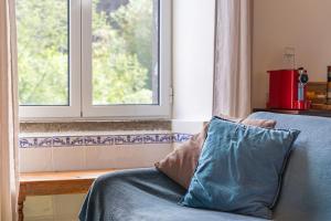 a blue couch with a pillow in front of a window at Gouveia Cottage in Seixal