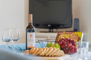 a bottle of wine and a basket of grapes and bread at Gouveia Cottage in Seixal