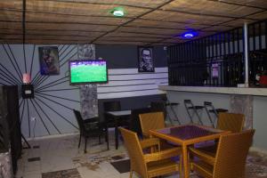 a dining room with a table and chairs and a tv at Mbre Hotel and Resorts in Uyo