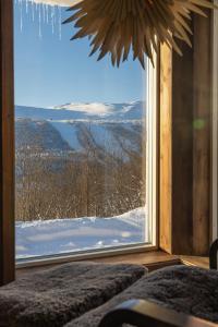 a room with a large window with a view of a snowy mountain at Röstavallens Högfjällshotell in Tänndalen