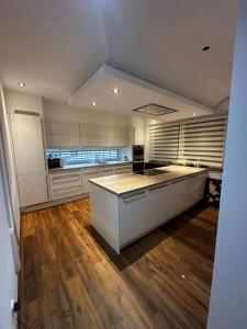 a large kitchen with white cabinets and a wooden floor at Zimmervermietung Wels 2 in Wels