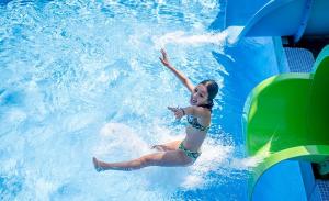 a young girl riding a water slide in a pool at Camping Enmar - Mobil home 3 pièces 4 personnes climatisé + TV MAE-5300 in Pineda de Mar