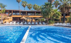 a swimming pool with chairs and a building with palm trees at Camping Enmar - Mobil home 3 pièces 4 personnes climatisé + TV MAE-5300 in Pineda de Mar