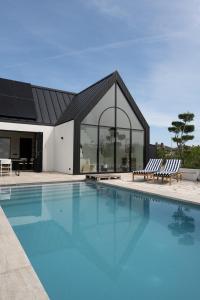 a swimming pool with two chairs and a building at 8 persons Wellness Villa Tulpenacker in Roelofarendsveen