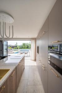 a kitchen with white cabinets and a view of a pool at 8 persons Wellness Villa Tulpenacker in Roelofarendsveen
