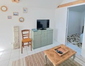 a living room with a tv and a coffee table at Aux Rives Tranquilles, appartement bord de Loire avec vue in Les Rosiers