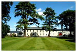 a large white house with trees in the yard at Roganstown Hotel & Country Club in Swords