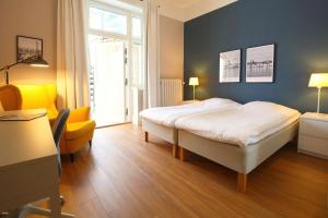 a bedroom with a bed and a yellow chair at Stationshuset bed and breakfast i Ed in Ed
