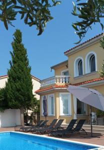 a villa with a swimming pool in front of a house at Villa Rosana in Rab