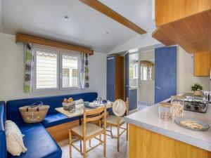 a living room with a blue couch and a kitchen at ZEcamping 4 étoiles pet friendly avec piscine chauffée et pataugeoire in Nesles-la-Vallée