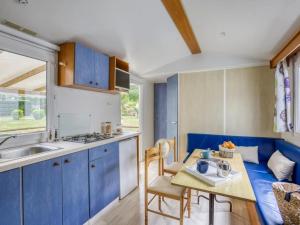 a kitchen with blue cabinets and a table with a table at ZEcamping 4 étoiles pet friendly avec piscine chauffée et pataugeoire in Nesles-la-Vallée