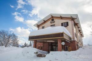 budynek pokryty śniegiem wokół niego w obiekcie Morino Lodge - Myoko w mieście Myoko