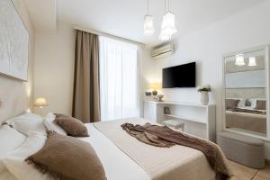 a white bedroom with a bed and a tv at Guest House Flores in Dubrovnik