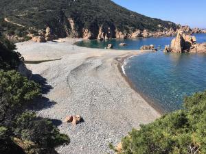 a sandy beach with rocks in the water at Aquafantasy rooms in Isola Rossa