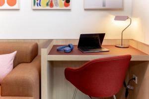 a room with a desk with a laptop and a red chair at Numa Madrid Fuencarral in Madrid