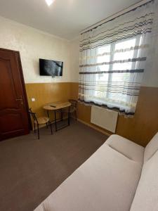 a room with a bed and a table and a window at Бордуляка 11 in Ternopil