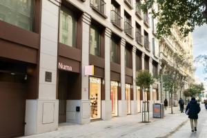 a woman walking down a street in front of a building at Numa Madrid Fuencarral in Madrid