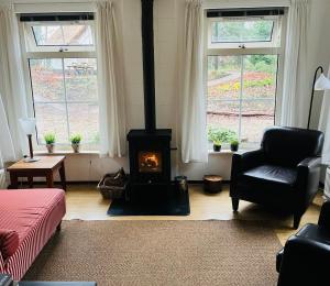 a living room with a stove and a couch and windows at De Compaenenhorst in IJhorst