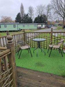a table and chairs on a deck with a fence at Parkview Billing Aquadrome in Great Billing