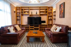 a living room with two leather couches and a television at Villa BALRA une maison d'hôtes au coeur du centre ville in Rabat