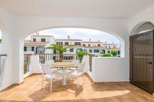 a dining room with a table and chairs on a balcony at Siesta Mar Apartamentos in Cala en Porter