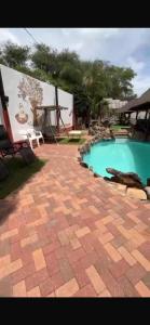 a swimming pool in a yard with a brick patio at Tourmaline GuestHouse in Windhoek