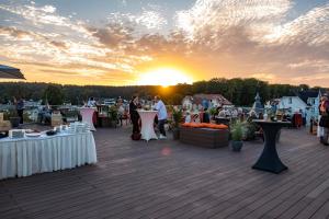 a group of people standing around tables on a deck with the sunset at SEETELHOTEL Kaiserstrand Beachhotel das Lifestyle-Hotel direkt am Strand in Bansin +55 photos