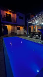 a blue pool in front of a house at night at Chalés Boqueirão beach in Japaratinga