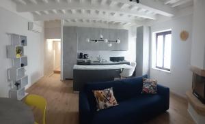 a living room with a blue couch and a kitchen at La terrazza del Papa in Pienza