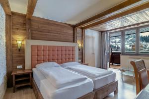 a bedroom with a large bed and a large window at Hotel Victoriya in Kaprun