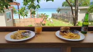 a table with two plates of food and a sandwich and french fries at Turtle Cove Resort in Siviri