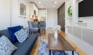a living room with a blue couch and a wooden table at Long Stay Close To Canary Wharf - Business Travelers, Contractors, Small Families in London