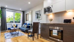 a kitchen and living room with a couch and a table at Long Stay Close To Canary Wharf - Business Travelers, Contractors, Small Families in London