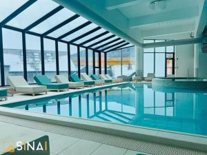 a pool in a building with chairs and a swimming pool at SINAI APH Apartments in Sinaia