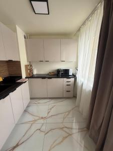 a kitchen with white cabinets and a marble floor at Apartament Grodzka in Wałbrzych
