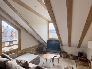 a living room with a couch and a tv at Atico de lujo en el Pirineo in El Pueyo de Jaca