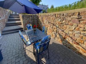 a table and chairs with an umbrella on a brick wall at Romantischer Aufenthalt mit Blick auf den Weinberg in Kinheim