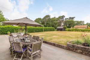 a table and chairs with an umbrella on a patio at 5 Bed in Walberswick oc-hlodg2 in Walberswick