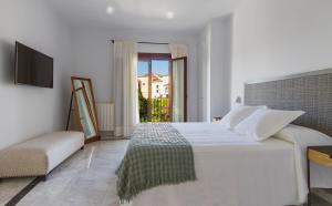 a white bedroom with a bed and a window at The Gorge House in Ronda