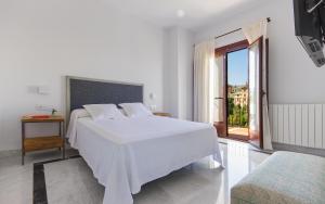 a white bedroom with a white bed and a window at The Gorge House in Ronda